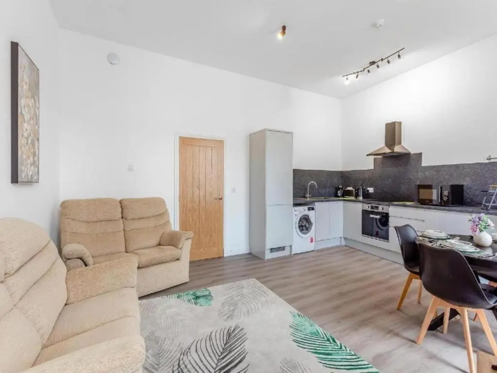 a living room with a couch and a table and a kitchen at Family - Central - Parking - Wifi - Sleeps 4 in Inverness