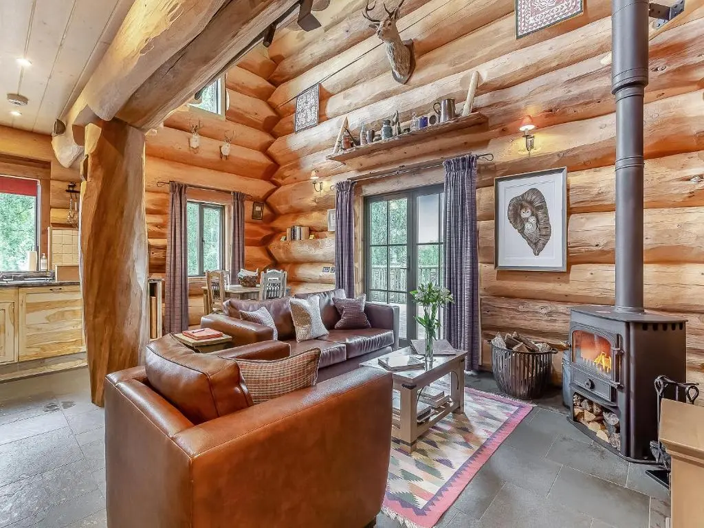 a living room with a couch and a fireplace in a log cabin at Cinclus - Uk50066 in Struy