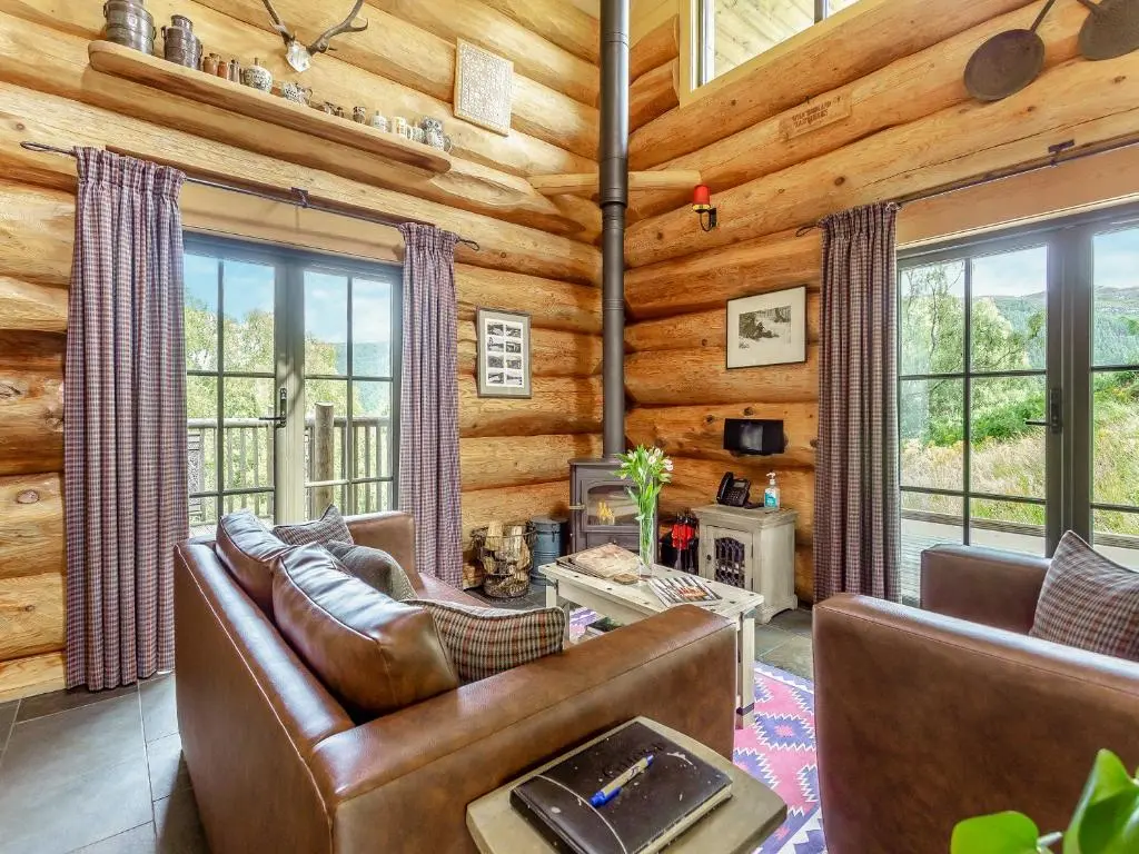 a living room with leather furniture in a log cabin at Strix - Uk50082 in Struy