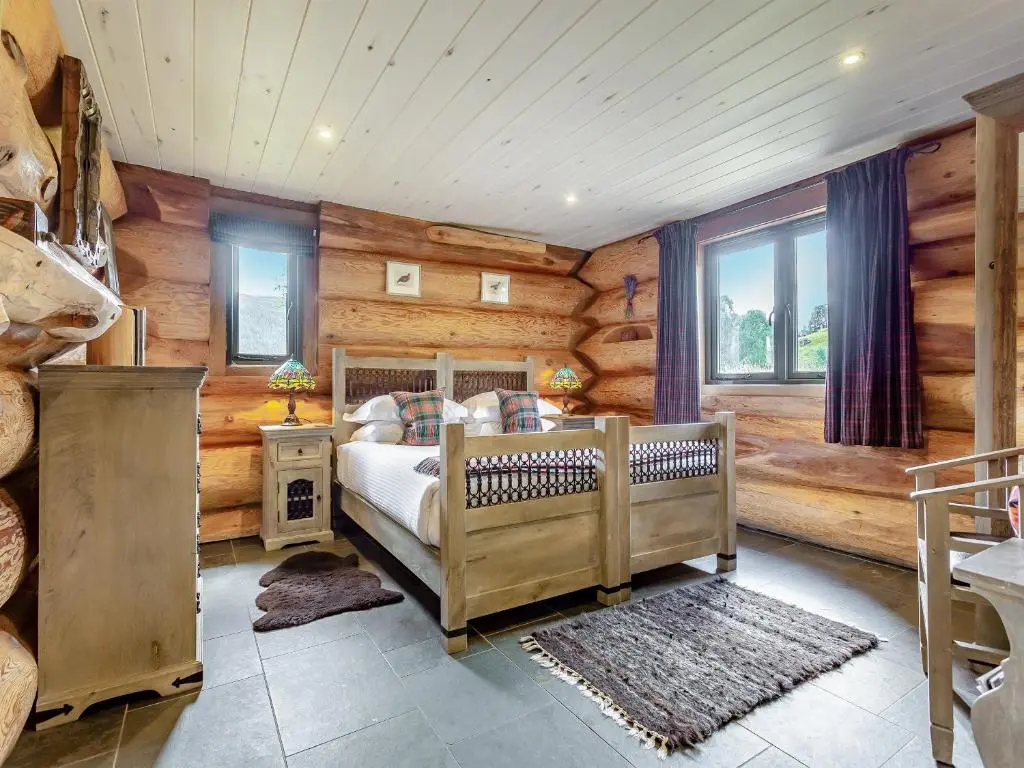 a bedroom with a bed in a room with wooden walls at Buteo - Uk50068 in Struy