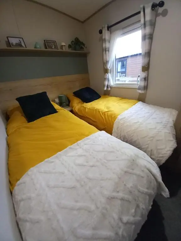 two beds in a room with yellow and white at Boat 32 in Boat of Garten