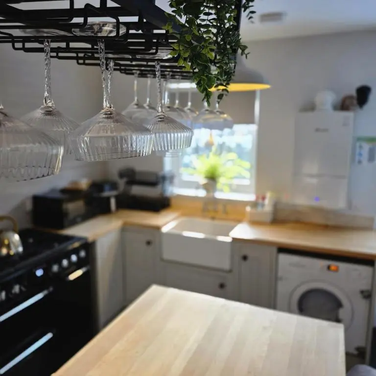 a kitchen with several wine glasses hanging from a rack at Shamus cottage in Alness