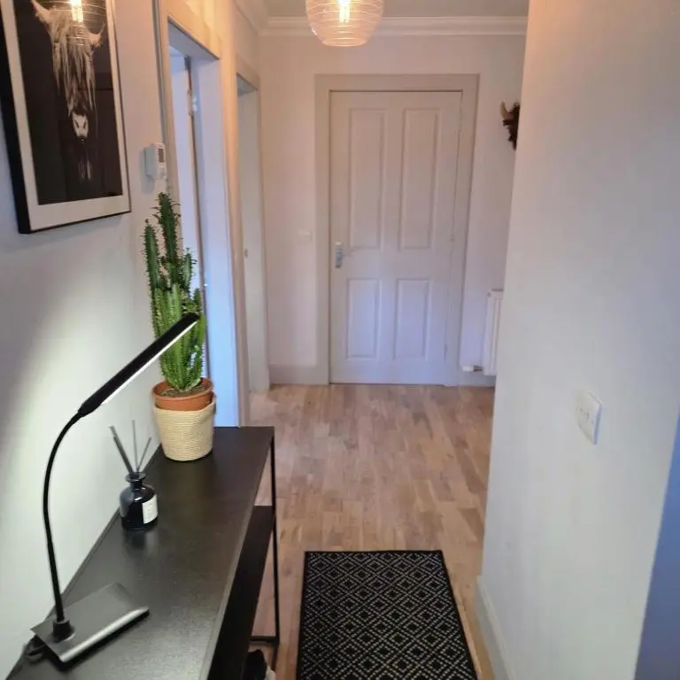 a room with a desk with a lamp and a door at Shamus cottage in Alness