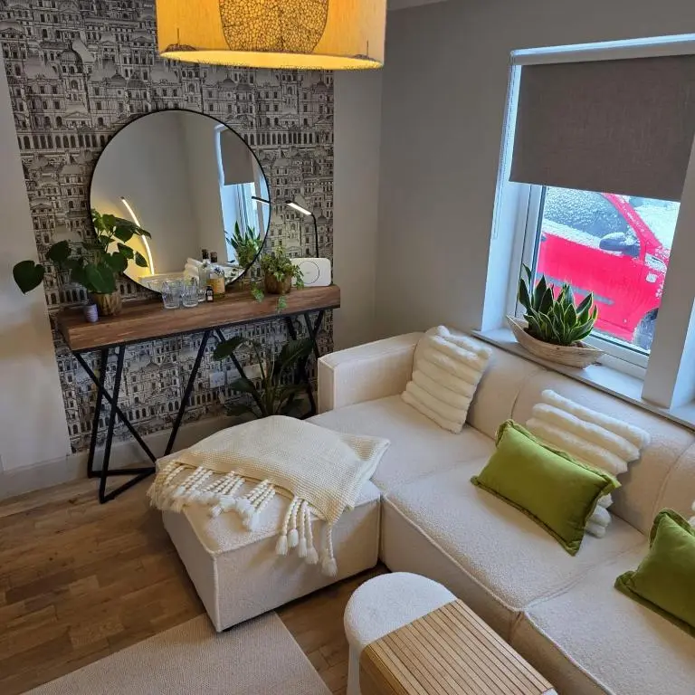 a living room with a white couch and a mirror at Shamus cottage in Alness