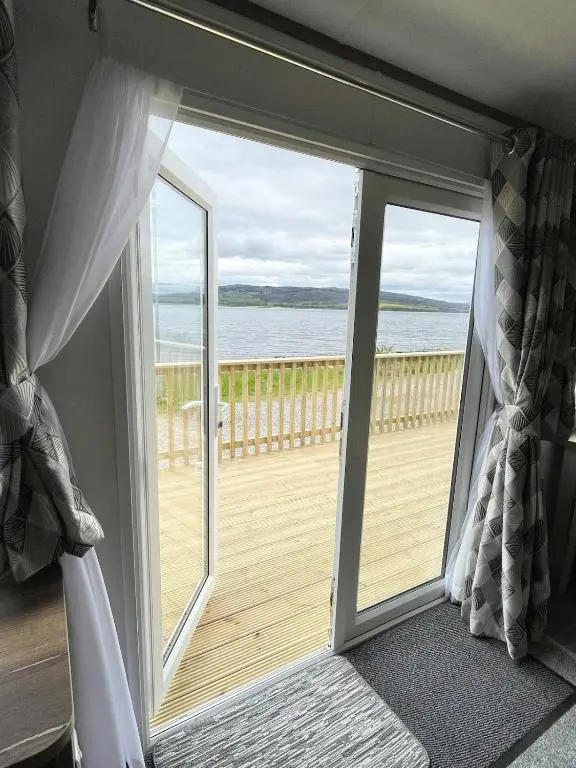 a door leading to a balcony with a view of the ocean at Brand New Beautiful Home close to Inverness in North Kessock