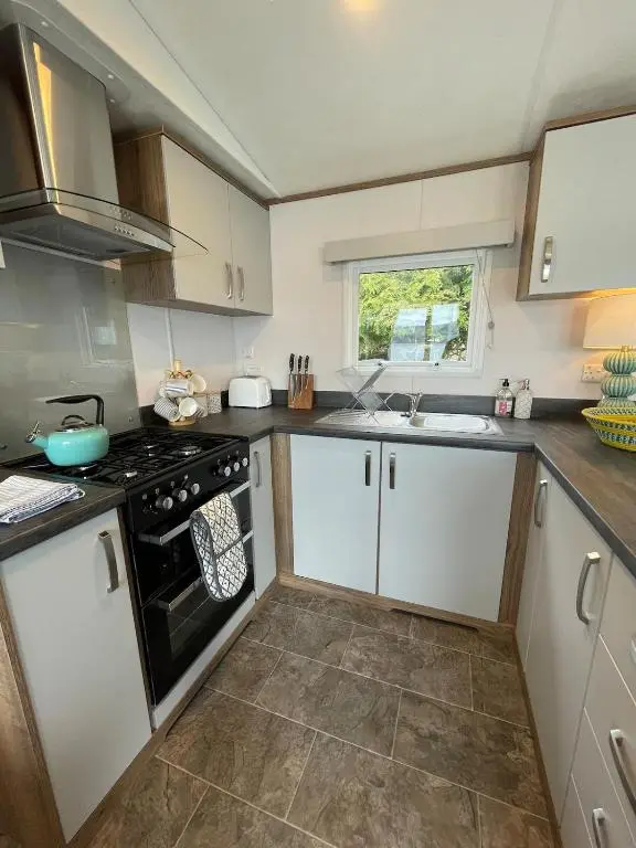 a kitchen with white cabinets and a black stove at Brand New Beautiful Home close to Inverness in North Kessock