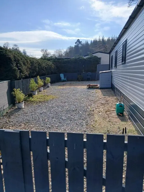 a backyard with a fence next to a house at The Robin's Nest in Fochabers