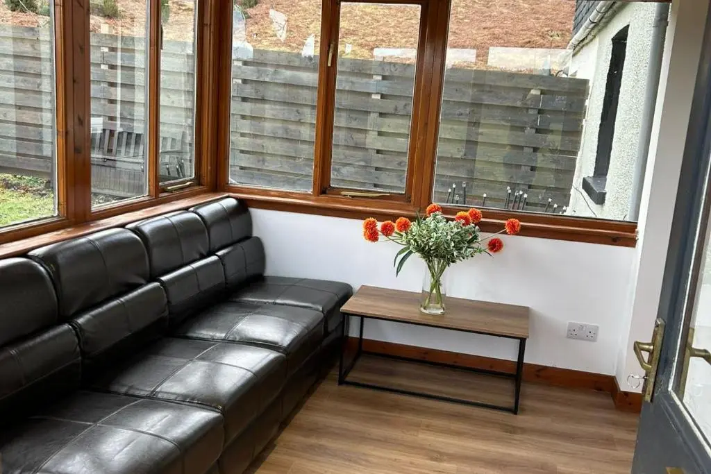a living room with a couch and a table with flowers at Hot tub - Garden - Bbq - Parking - Pets - Sleeps 6 in Strathpeffer