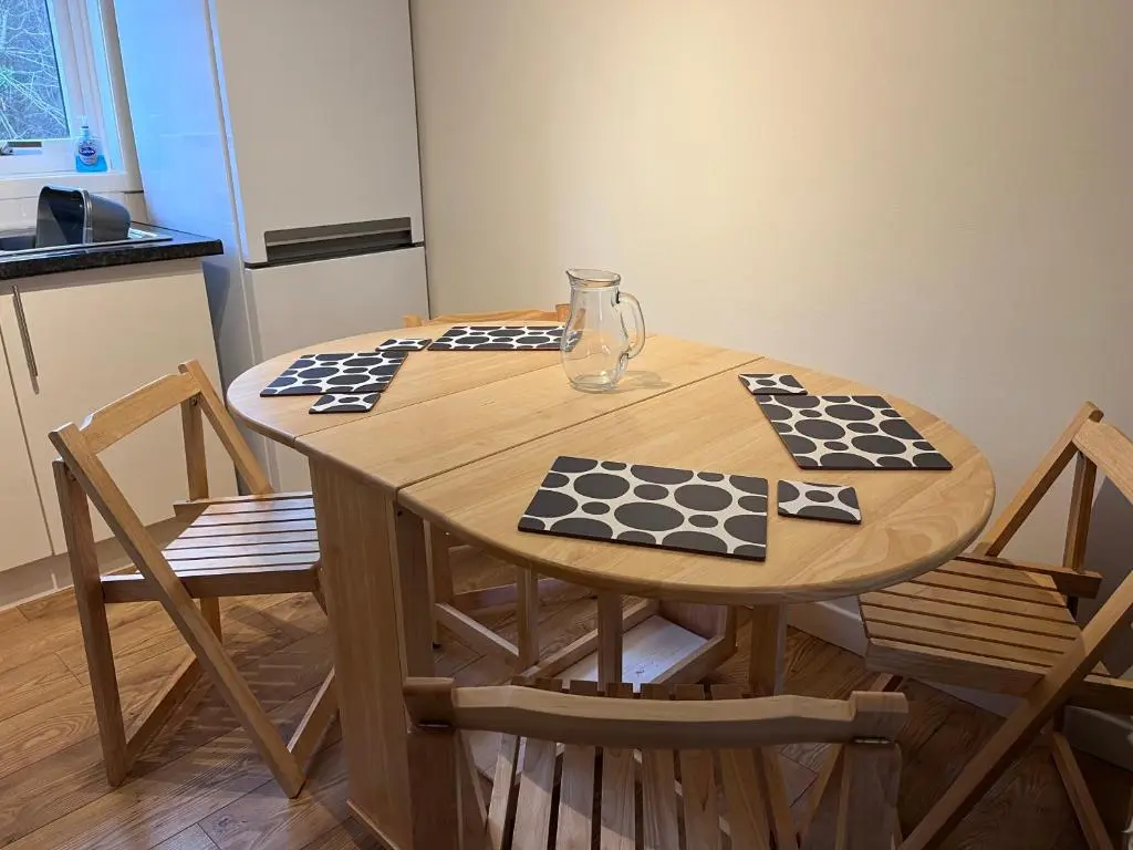 a wooden table in a kitchen with two chairs at Millburn Court Apartment in Inverness