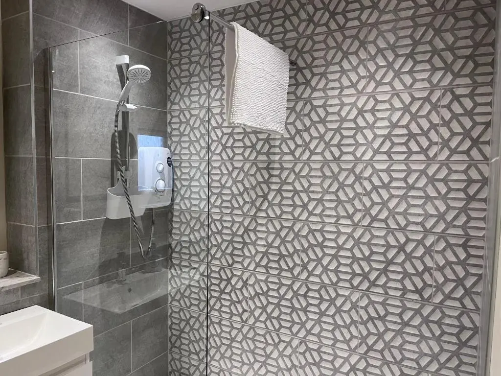 a bathroom with a shower with a black and white patterned wall at Millburn Court Apartment in Inverness