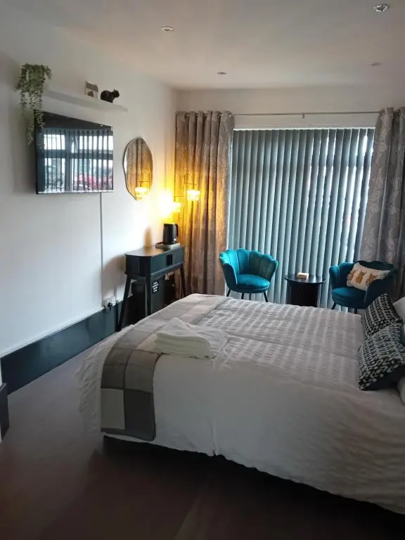 a bedroom with a large bed and two blue chairs at The Snug on The Brae in Inshes