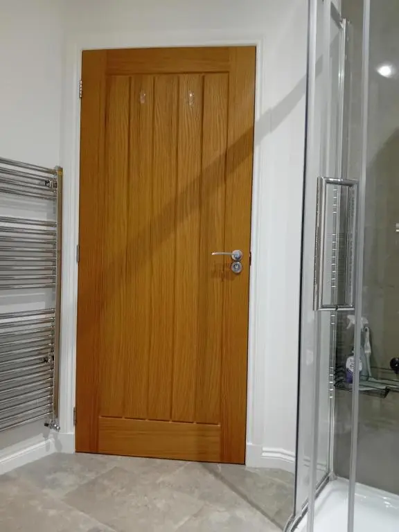a wooden door in a room with a shower at The Snug on The Brae in Inshes