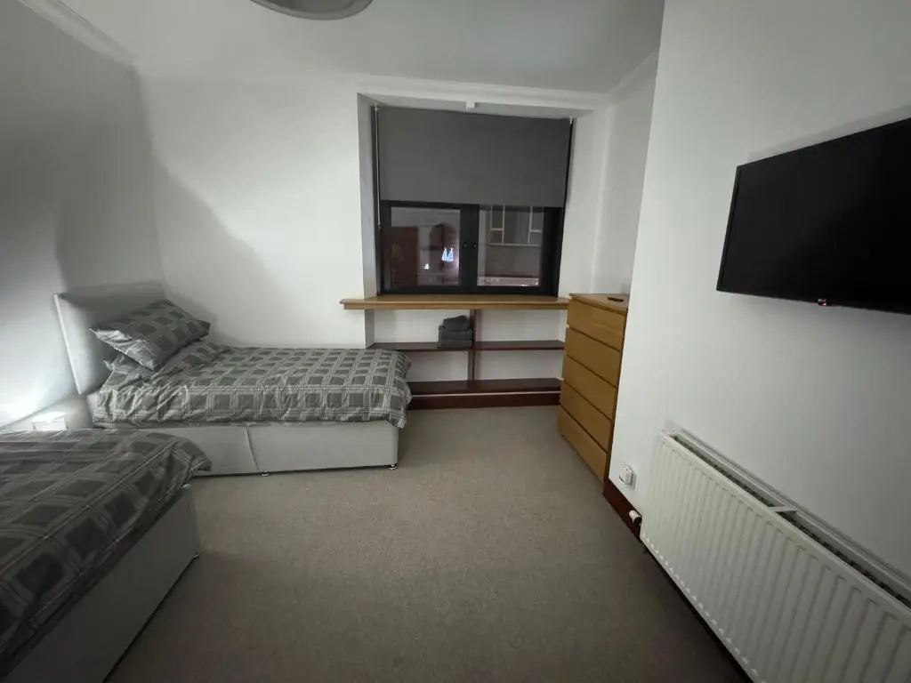 a bedroom with two beds and a flat screen tv at TSB Accommodation in Turriff