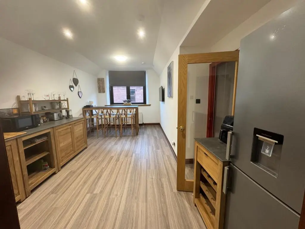 a kitchen with a refrigerator and a dining room at TSB Accommodation in Turriff