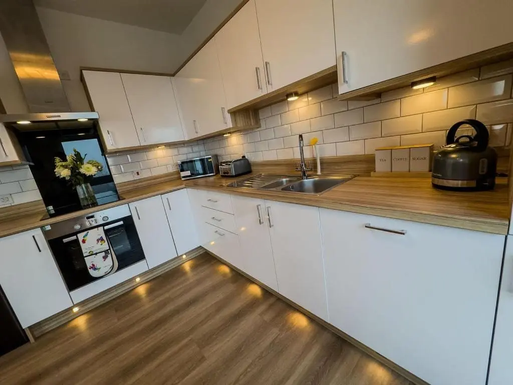 a kitchen with white cabinets and a sink at Beinn View in Inverness