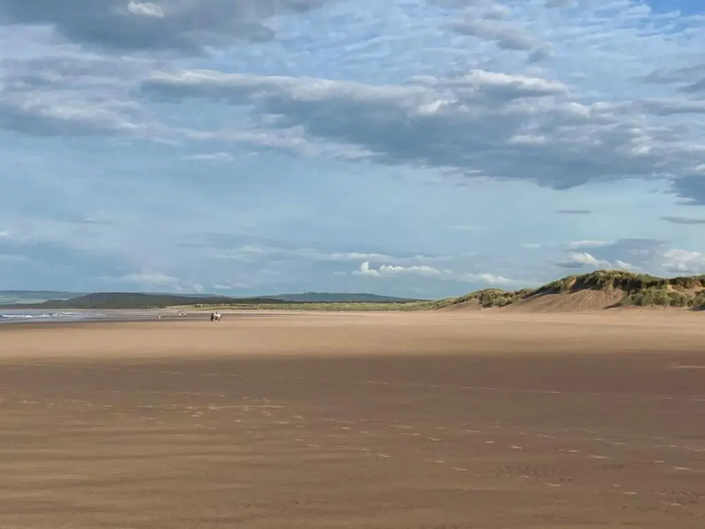 a sandy beach with people walking on the sand at Moray Coast getaway in Lossiemouth