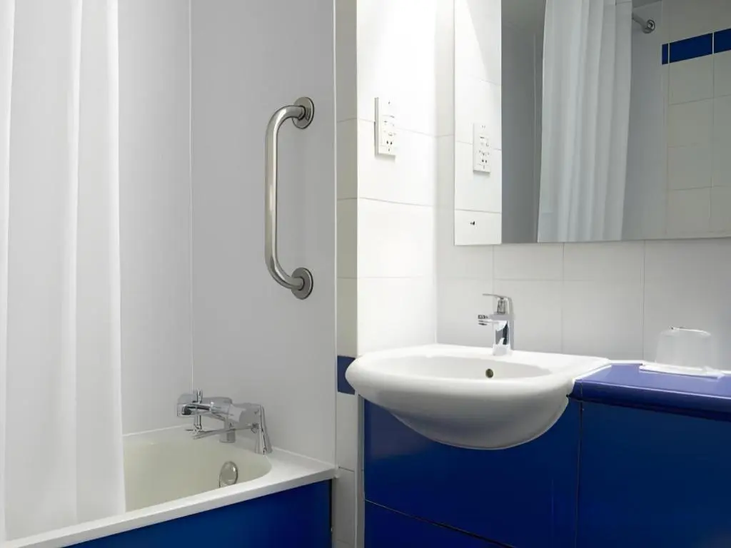 a bathroom with a sink and a mirror and a tub at Travelodge Inverness Fairways in Inshes
