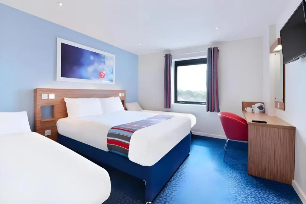 a hotel room with two beds and a tv at Travelodge Aberdeen Bucksburn in Aberdeen