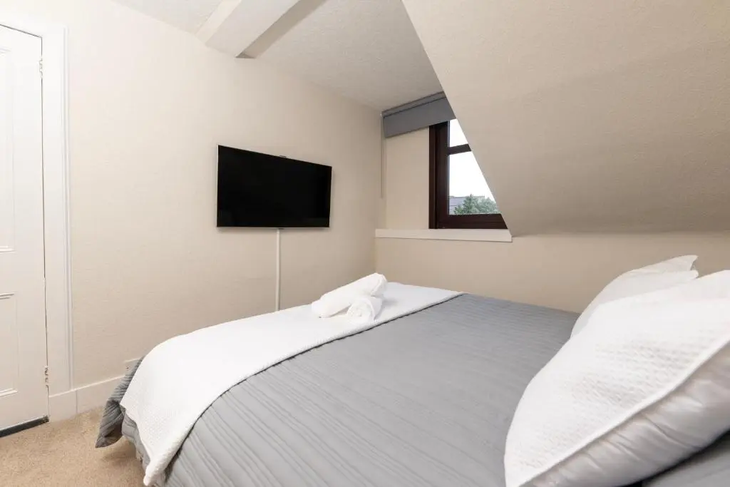 a bedroom with a bed and a tv on the wall at Century House - 4BR - Free Parking - City Centre in Inverness