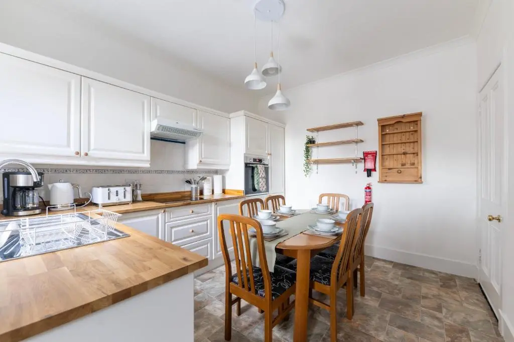 a kitchen with a table and chairs in a kitchen at Century House - 4BR - Free Parking - City Centre in Inverness