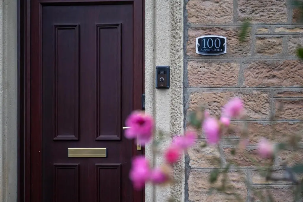 a door with a sign that reads next to pink flowers at Century House - 4BR - Free Parking - City Centre in Inverness