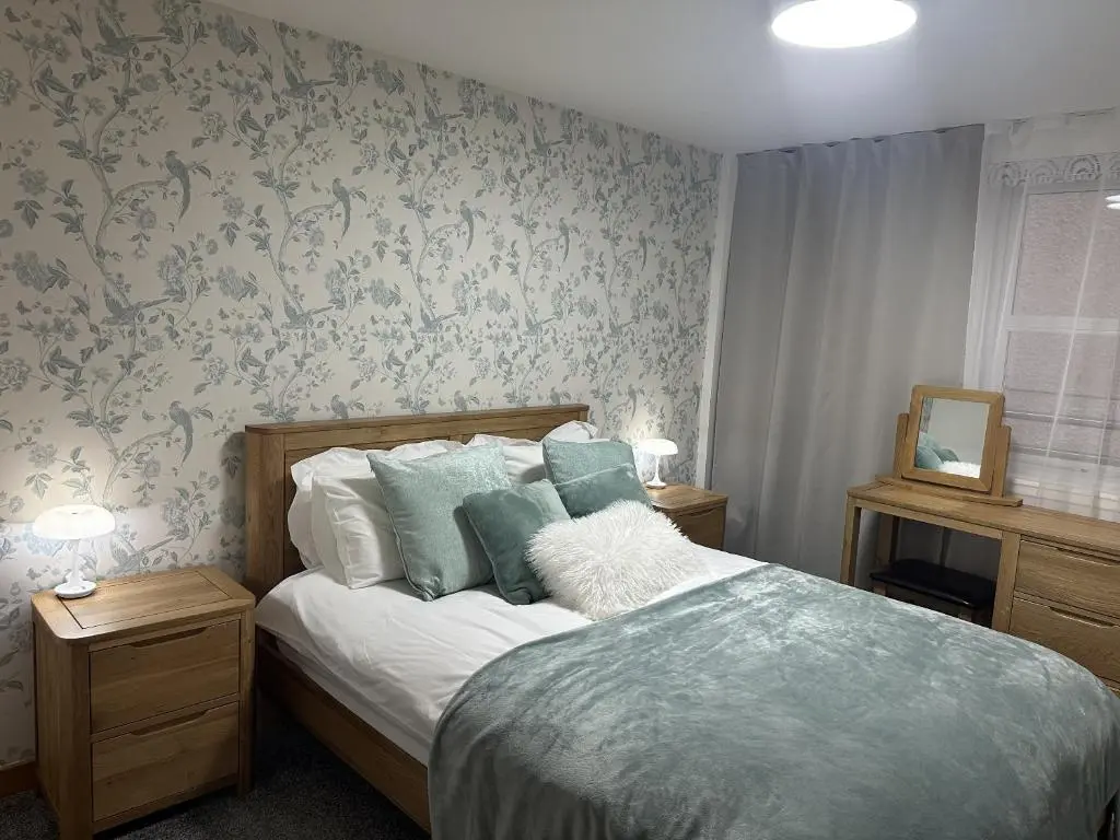 a bedroom with a bed with blue floral wallpaper at LaScala Apartment in Inverness