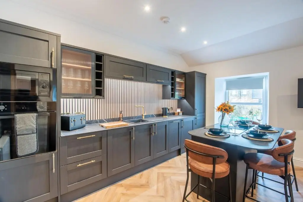 a kitchen with black cabinets and a table with chairs at Luxury New Inverness Apartment in a Prime Location in Inverness