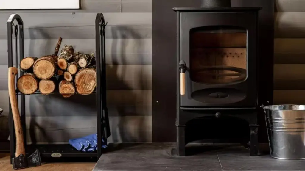 a black stove with a pile of logs next to at Cateran Rest in Kirkmichael