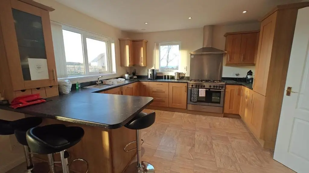 a kitchen with wooden cabinets and a black counter top at 3 Bed in Drybridge oc-w34891