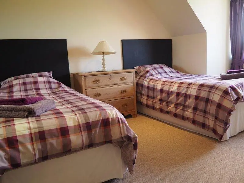 a bedroom with two beds and a dresser with a lamp at 3 Bed in Drybridge oc-w34891