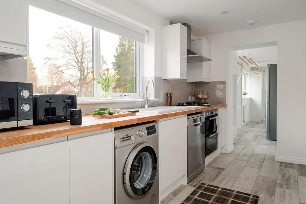 a kitchen with white cabinets and a washer and dryer at Inshlea - Seasgair Lodges in Insh