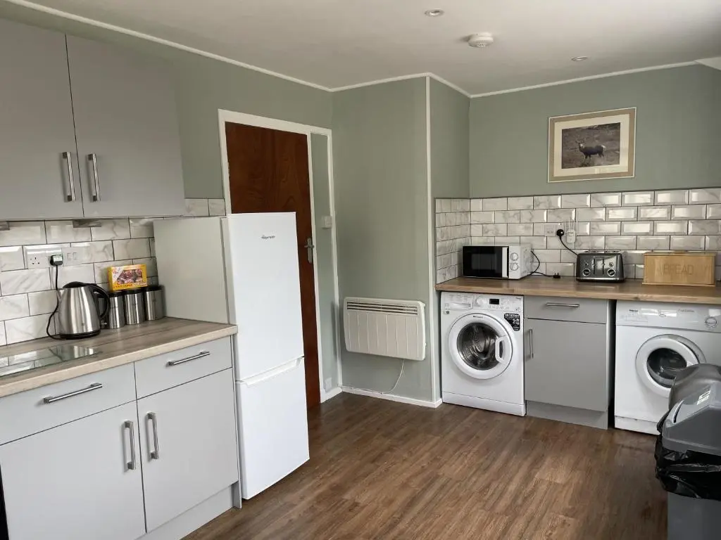 a kitchen with a refrigerator and a washer and dryer at Crianlarich Cottage in Fort Augustus
