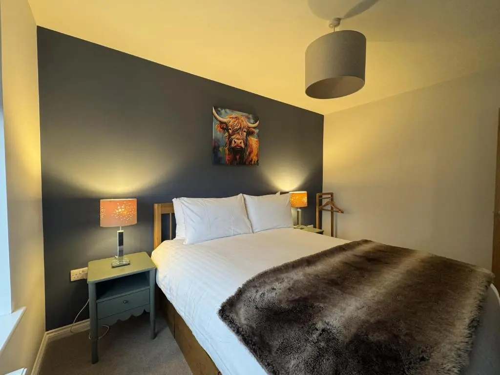 a bedroom with a bed and a table with two lamps at Sunny Ridge in Fort Augustus