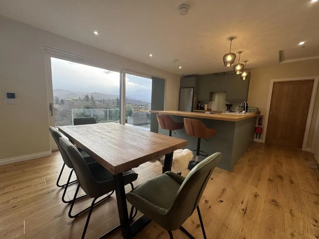 a dining room with a table and chairs and a kitchen at Sunny Ridge in Fort Augustus