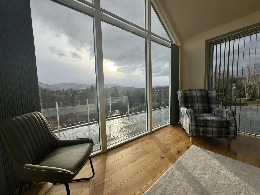 a living room with two chairs and a large window at Sunny Ridge in Fort Augustus