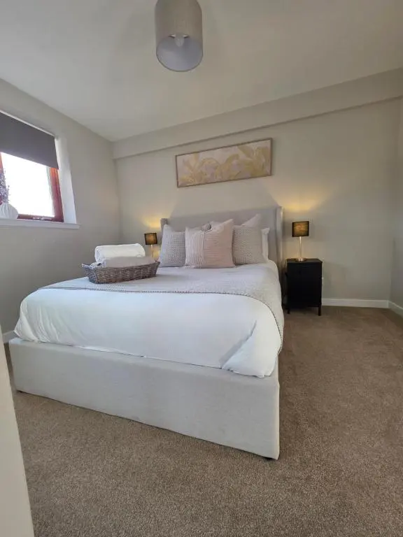 a bedroom with a large white bed with pillows at Riverside View in Inverness
