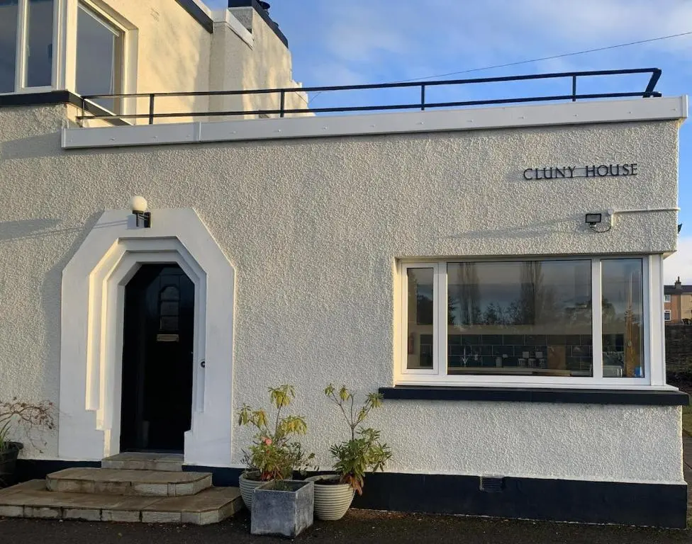 a white building with a black door and a window at Cluny Corner in Inverness