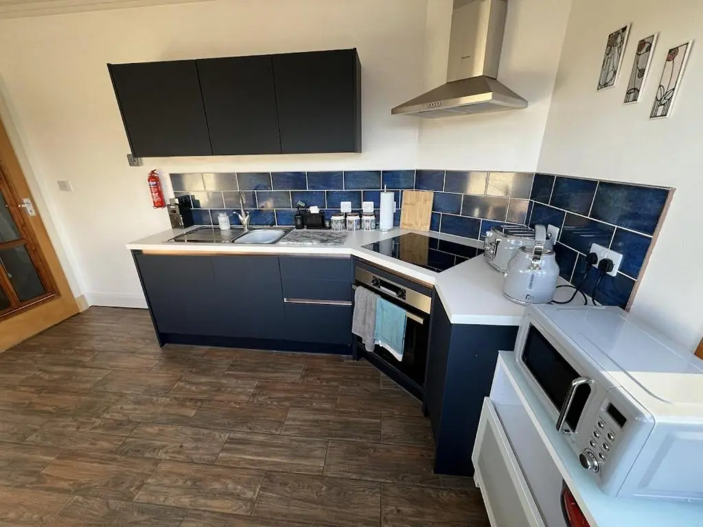 a kitchen with blue tiled walls and a counter top at Cluny Corner in Inverness