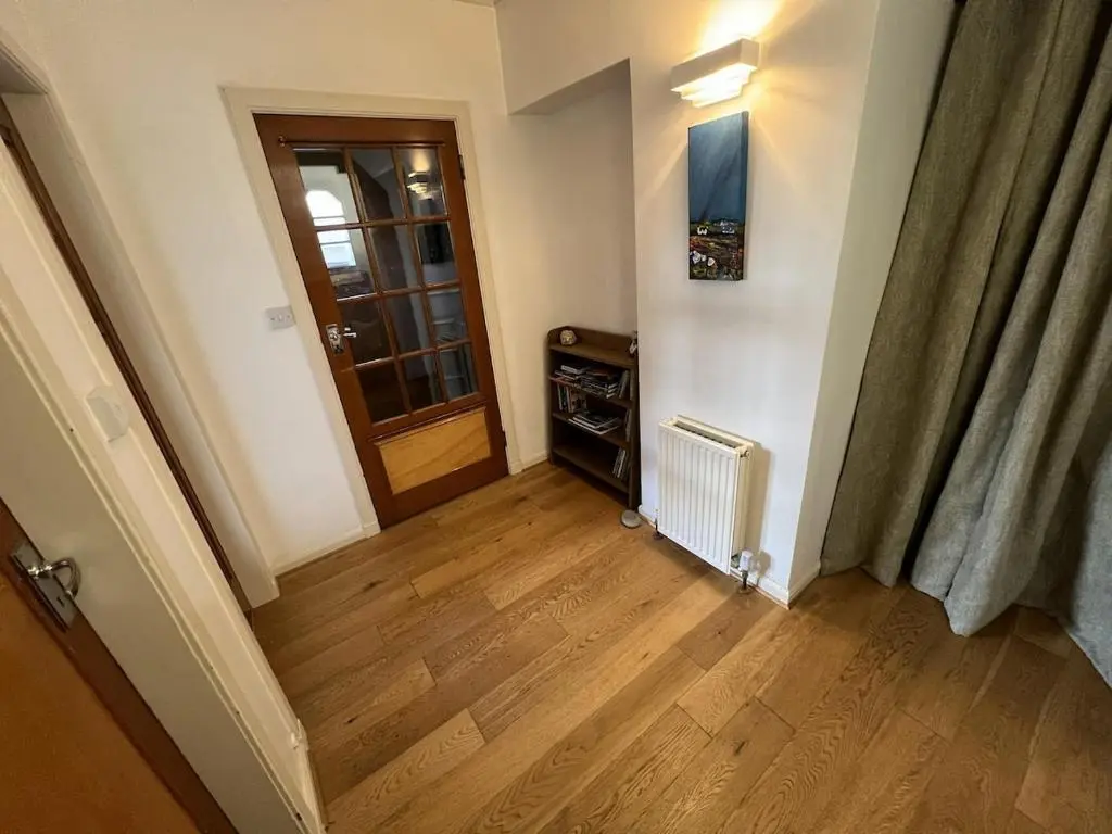 a hallway with a wooden floor and a door at Cluny Corner in Inverness