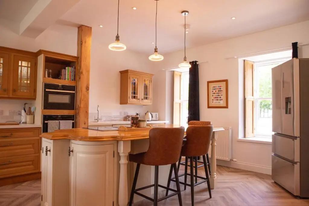 a kitchen with a island with bar stools at Calder House, Fochabers in Fochabers