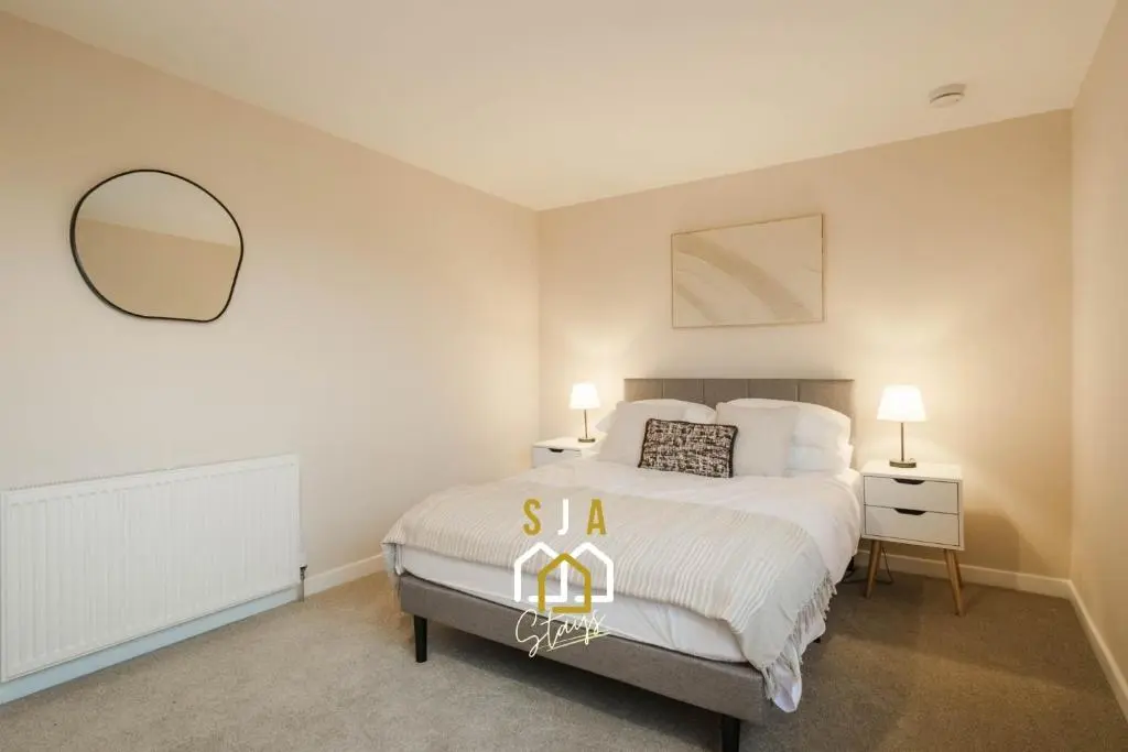 a bedroom with a large white bed and a mirror at Fraserburgh Stay - SJA Stays - Modern 2 Bed Apartment in Fraserburgh