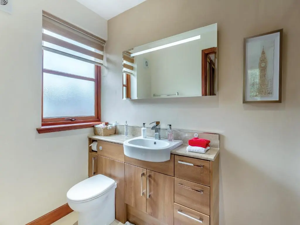 a bathroom with a sink and a toilet and a mirror at Cosy Ness in Inverness