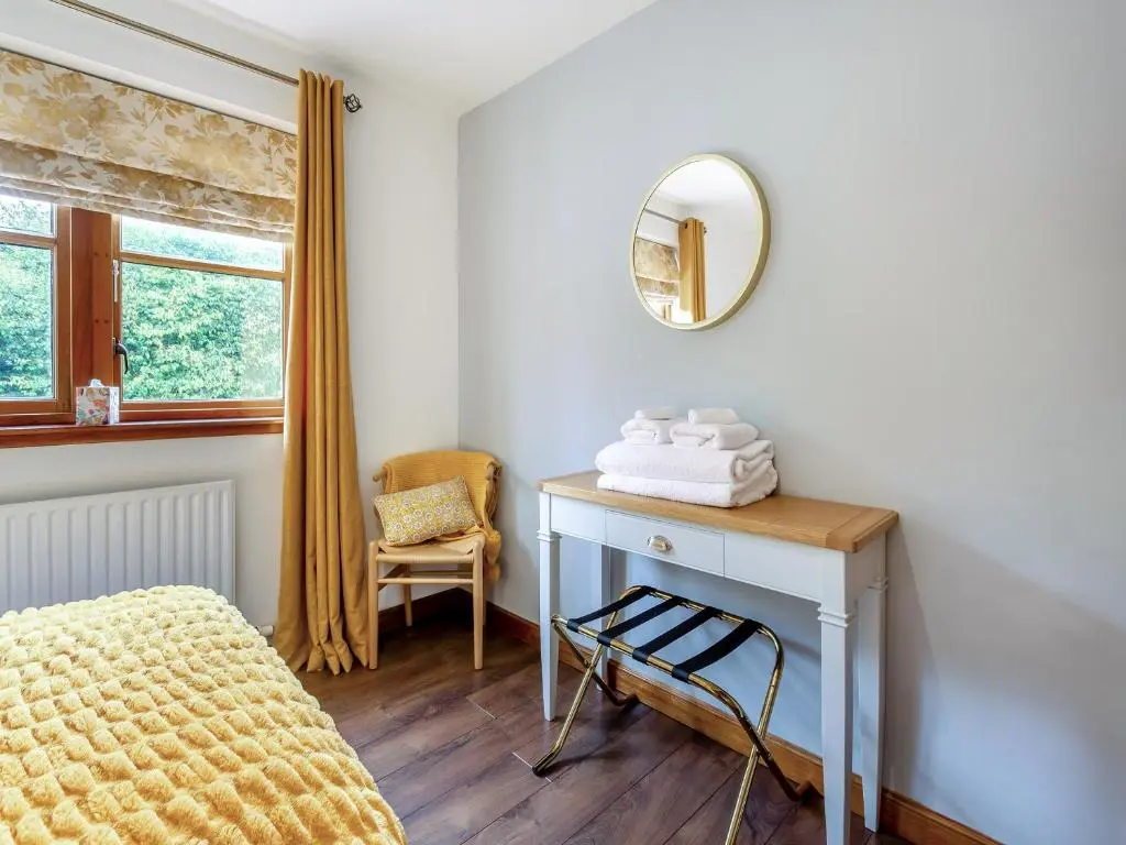 a bedroom with a dressing table and a mirror at Cosy Ness in Inverness