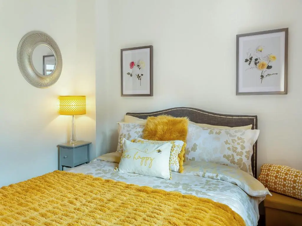 a bedroom with a bed with a yellow blanket at Cosy Ness in Inverness
