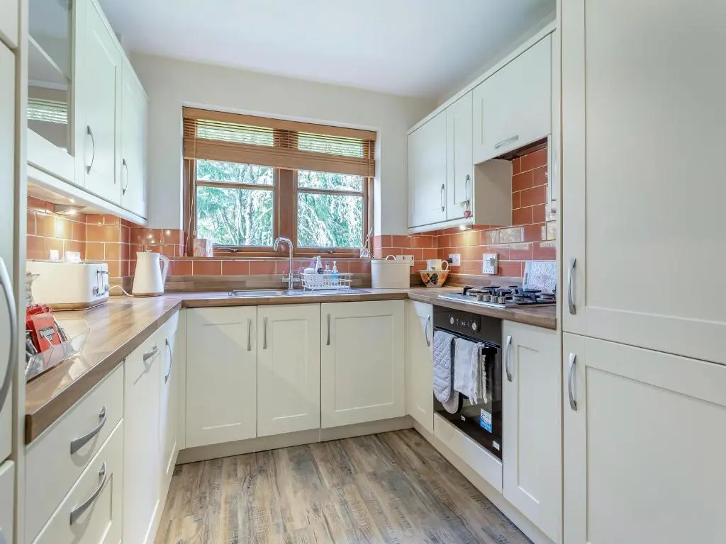 a white kitchen with white cabinets and a sink at Cosy Ness in Inverness