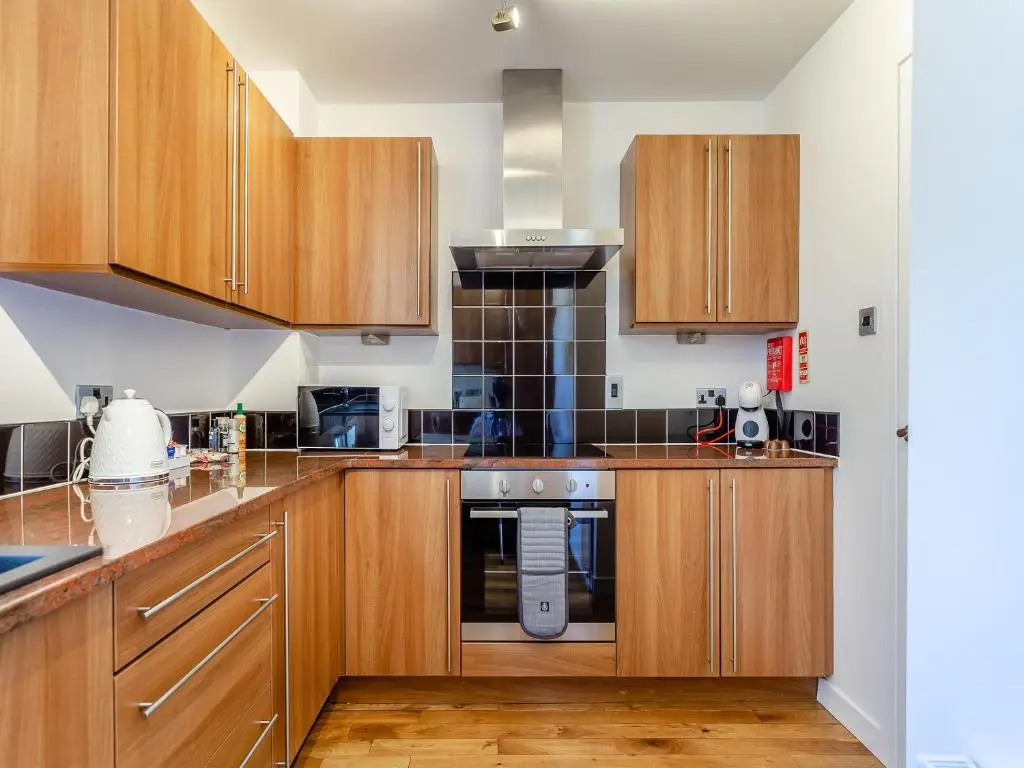 a kitchen with wooden cabinets and a stove at Inverness Highland Apartment in Inverness