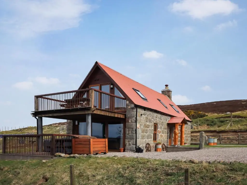 a building with a balcony on top of it at Kestrel Cottage in Rogart