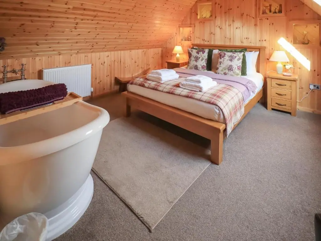 a bedroom with a bed and a tub in a room at Kestrel Cottage in Rogart