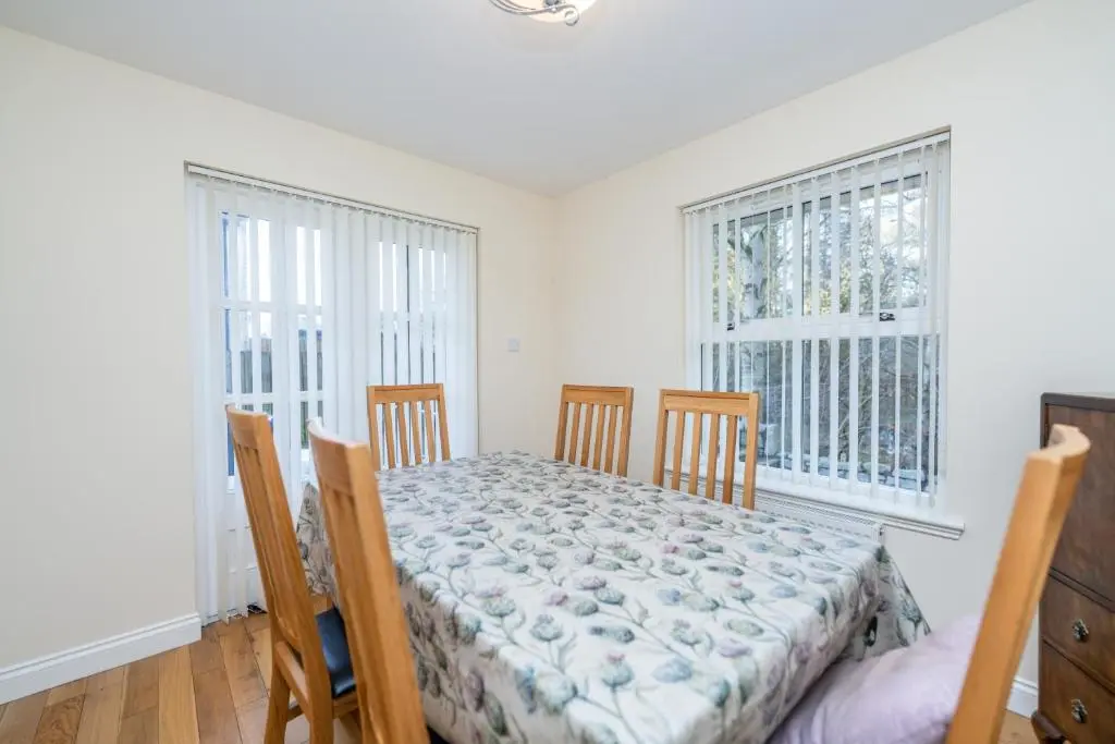a dining room with a table and chairs and two windows at Abbey View in Old Deer
