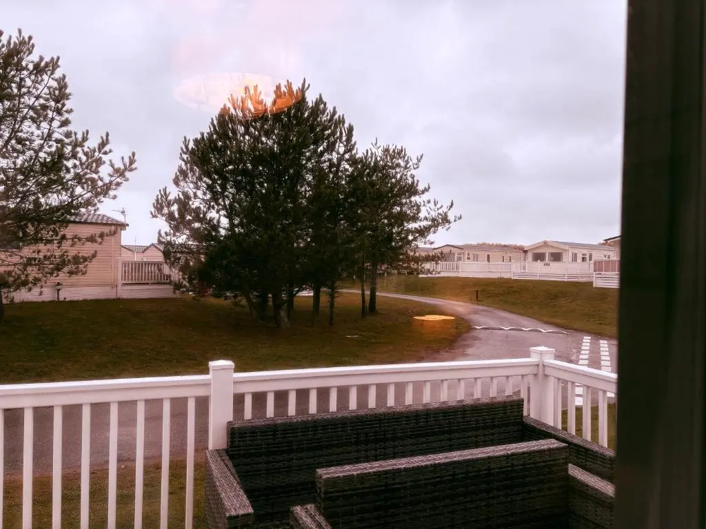 a porch with a white fence and stairs and trees at Sunset villa in Lossiemouth